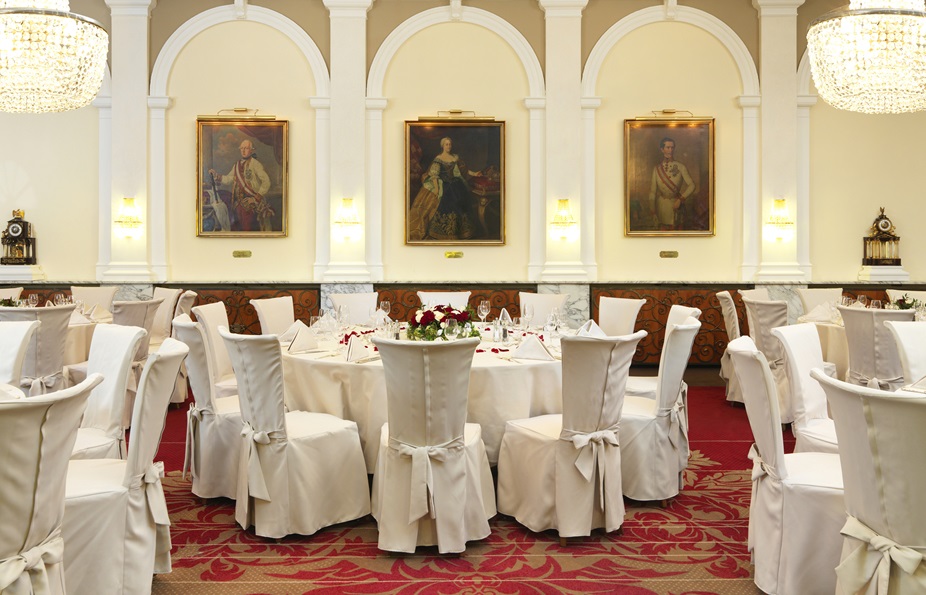 Interior view of a fine dining area with round tables, white tablecloths and floral centerpieces